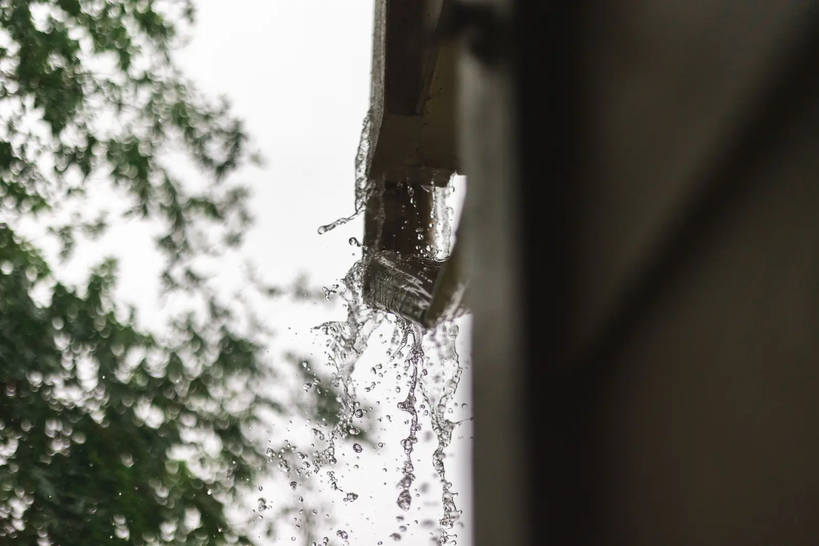Regenwasser läuft während eines starken Schauers über den Rand einer Dachrinne