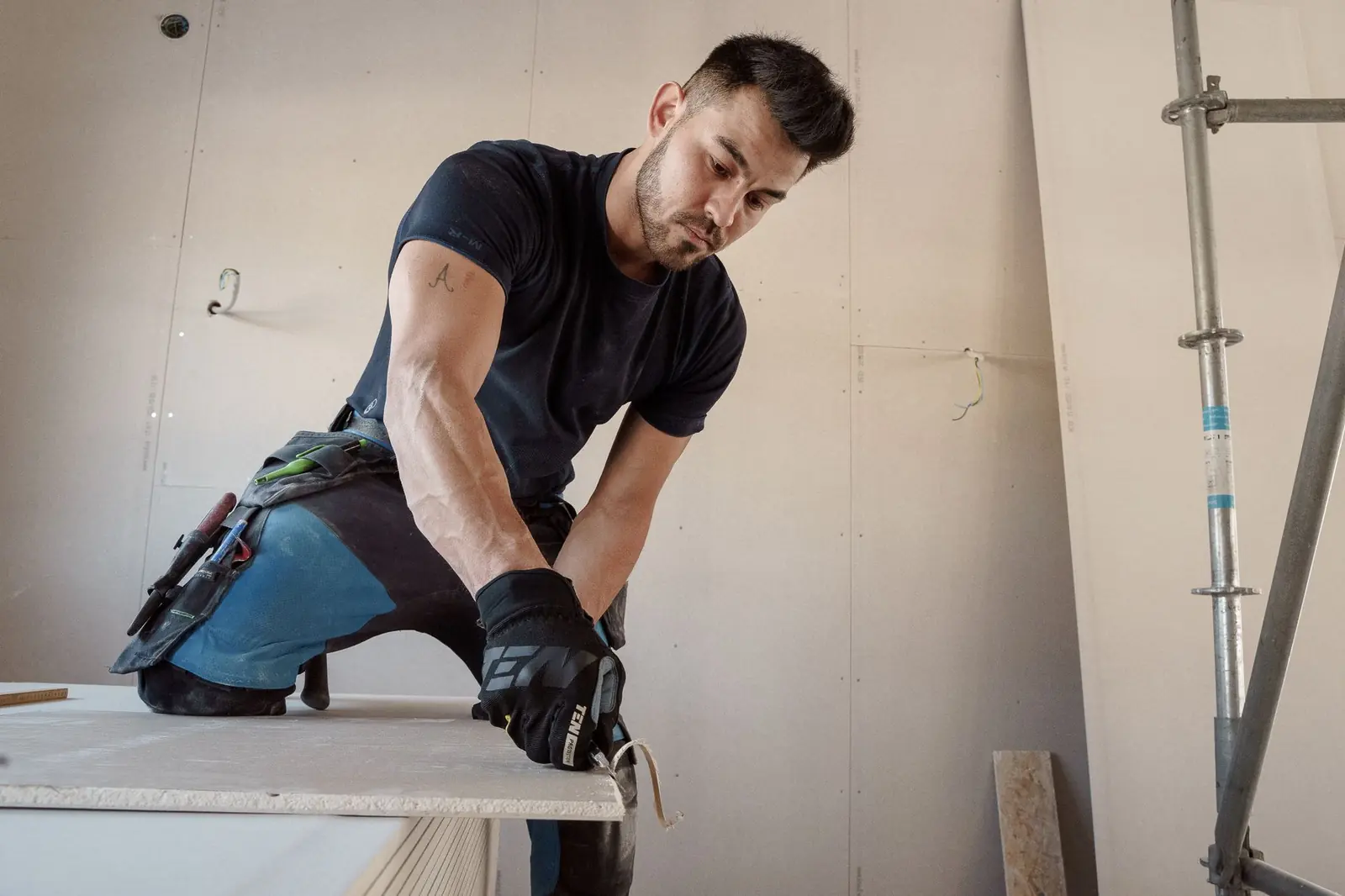Handwerker schneidet ein rechteckiges Flickstück aus einer Gipskartonplatte zu
