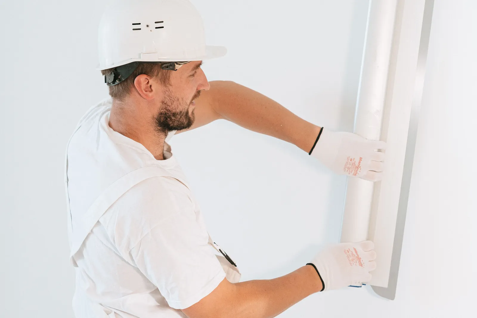 Handwerker richtet eine weiße Gipskartonplatte an einer Unterkonstruktion aus