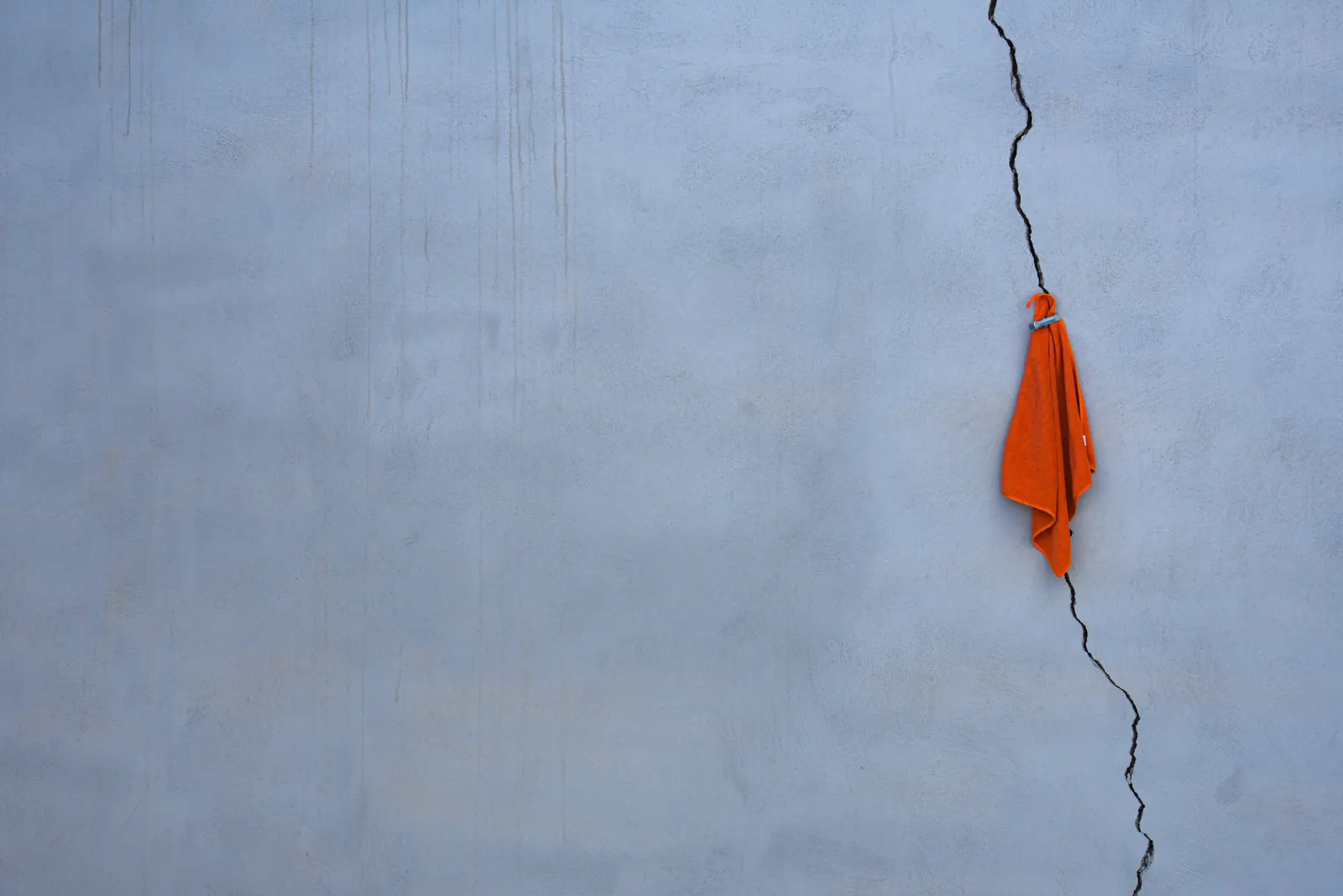 Ein breiter senkrechter Riss verläuft durch eine blaue Innenwand neben einem orangefarbenen Handtuch