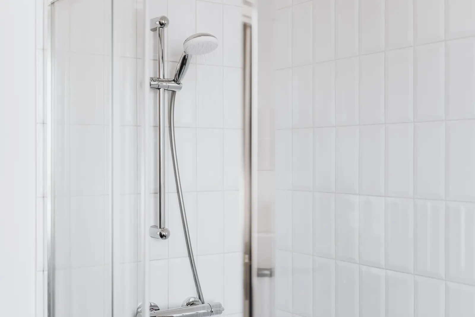 Weiße Dusche mit gefliesten Anschlussbereichen und Chromarmatur