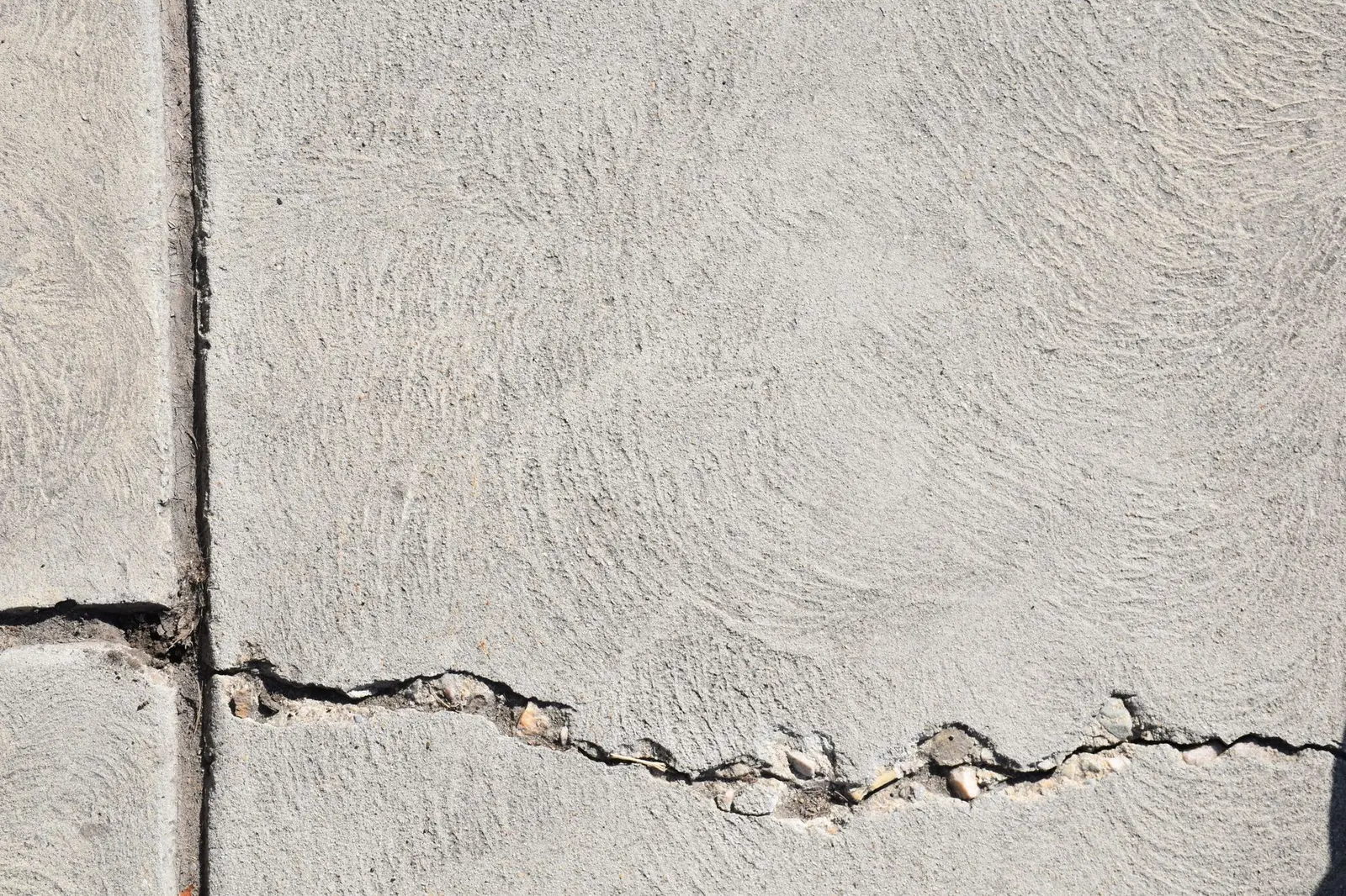 Abgeplatzte und gerissene Betonoberfläche mit sichtbarem Zuschlag