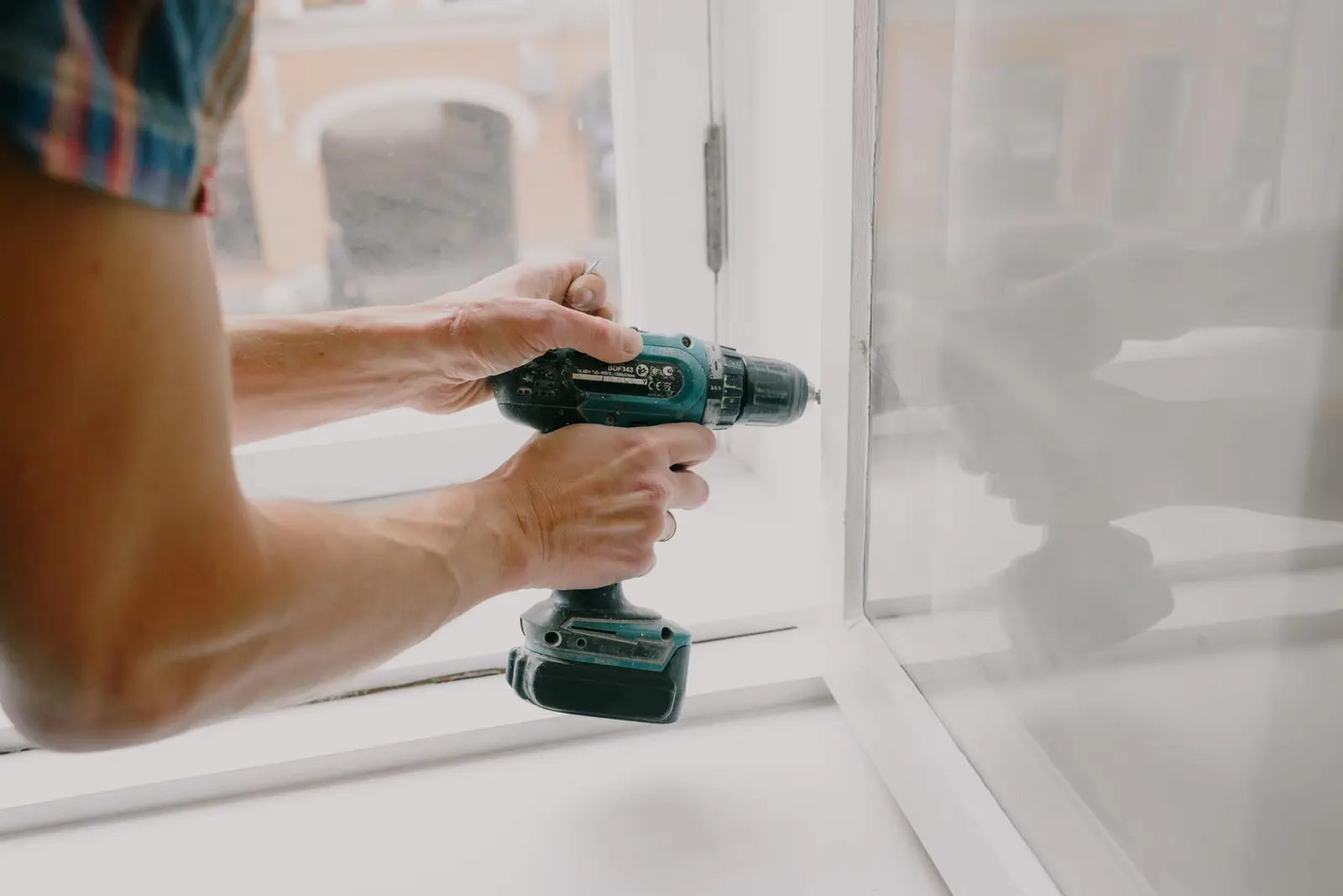 Handwerker arbeitet am Beschlag eines geöffneten weißen Fensters