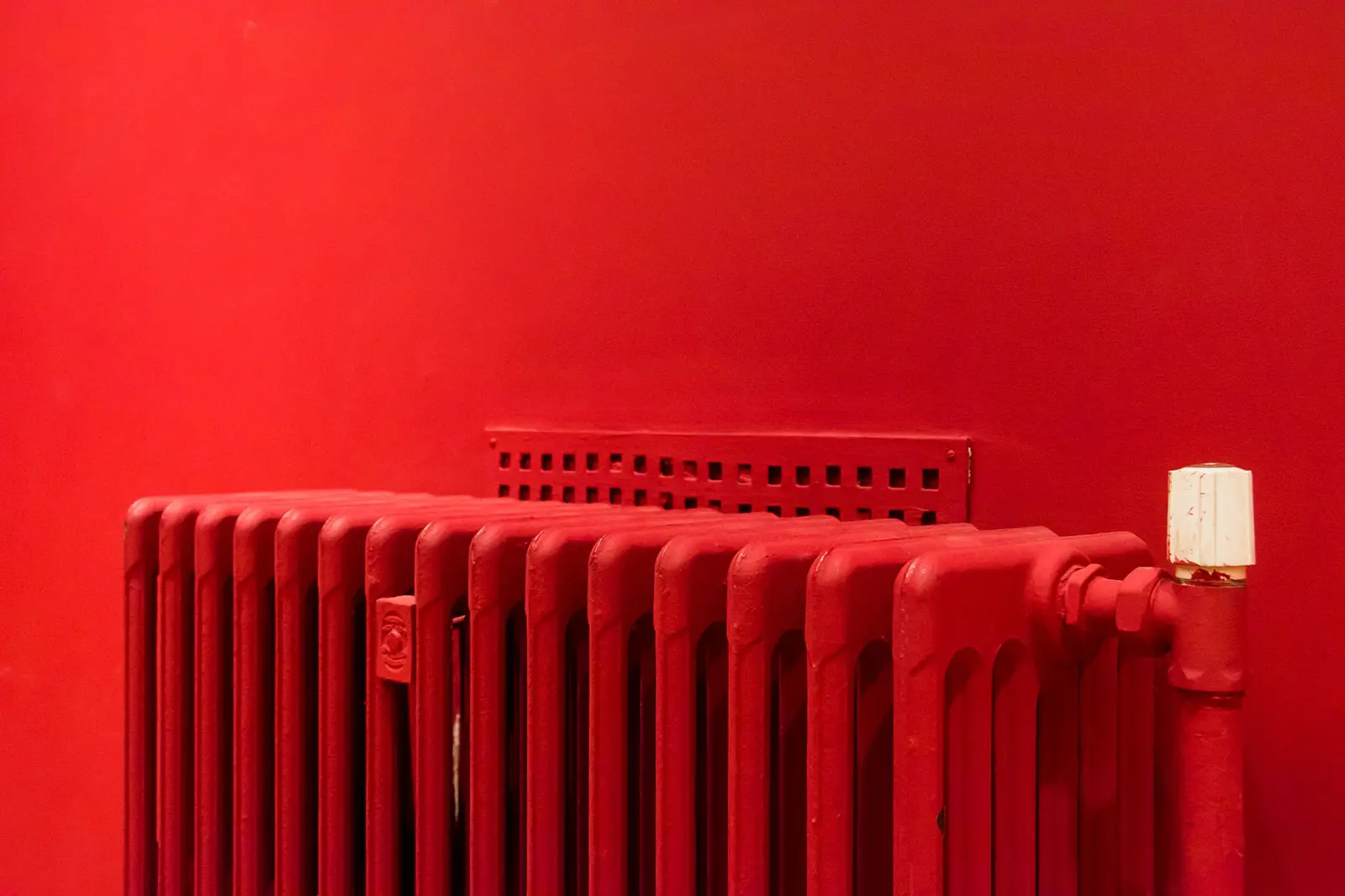Rot lackierter Rippenheizkörper vor einer ebenfalls roten Wand