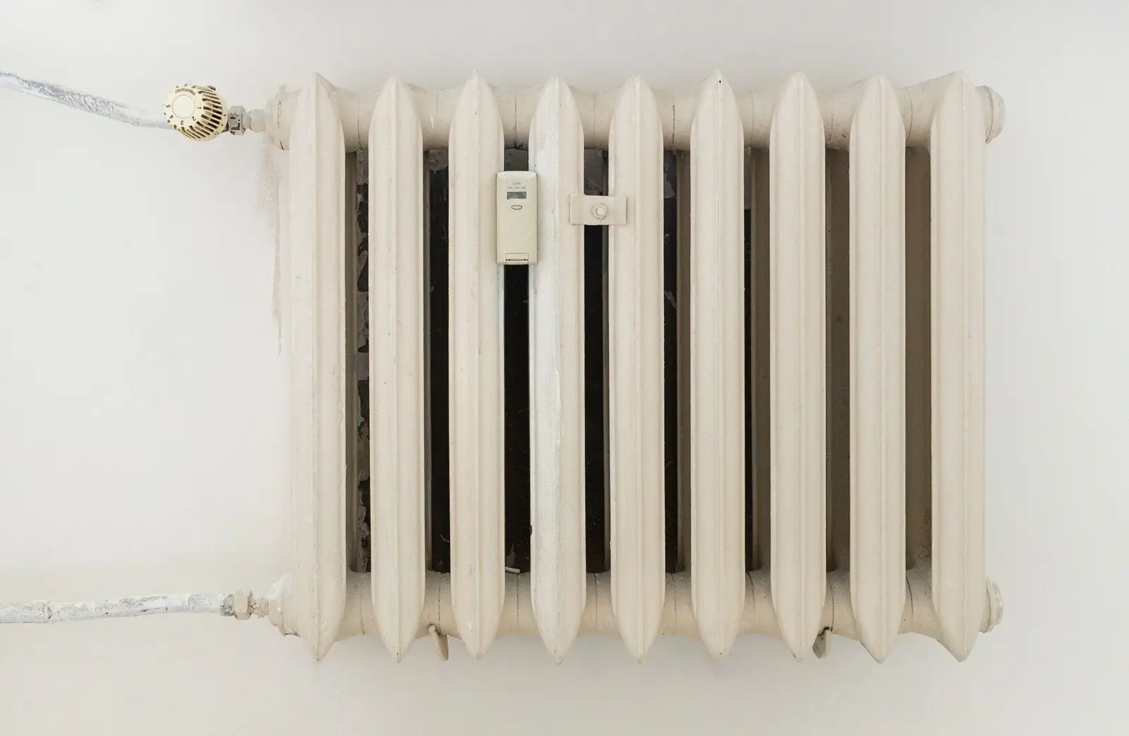 Klassischer weißer Heizkörper mit Thermostatventil an der linken Seite