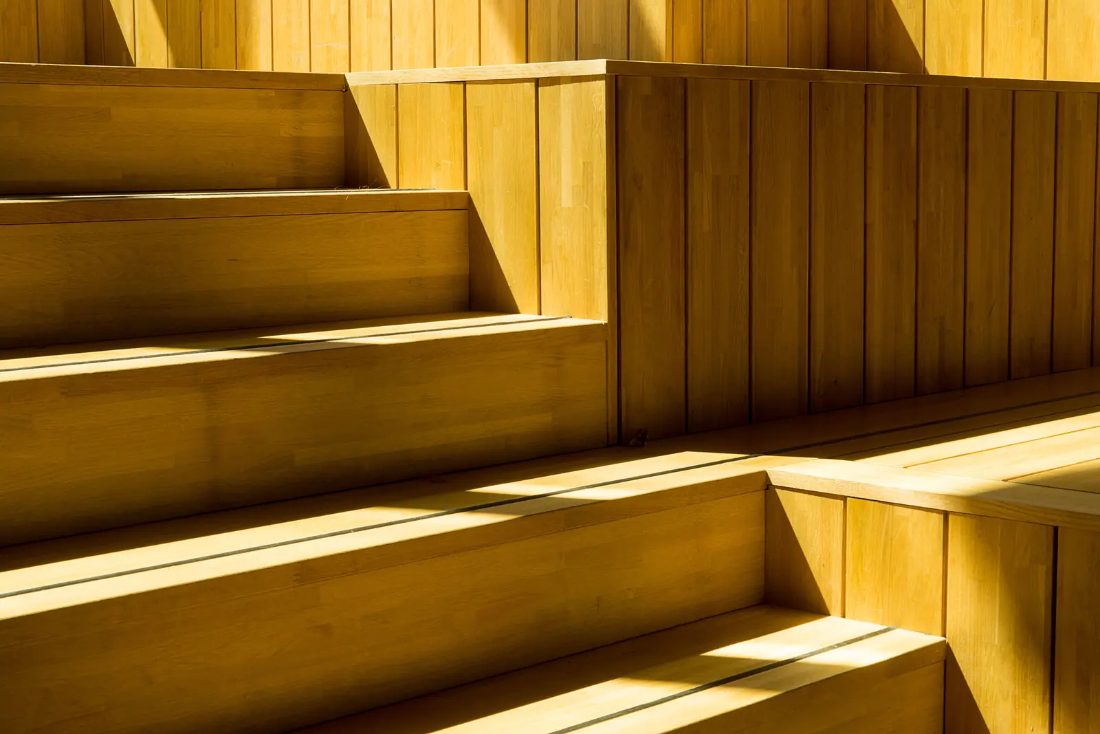 Nahaufnahme einer Holztreppe mit sichtbaren Tritt- und Setzstufen im Sonnenlicht