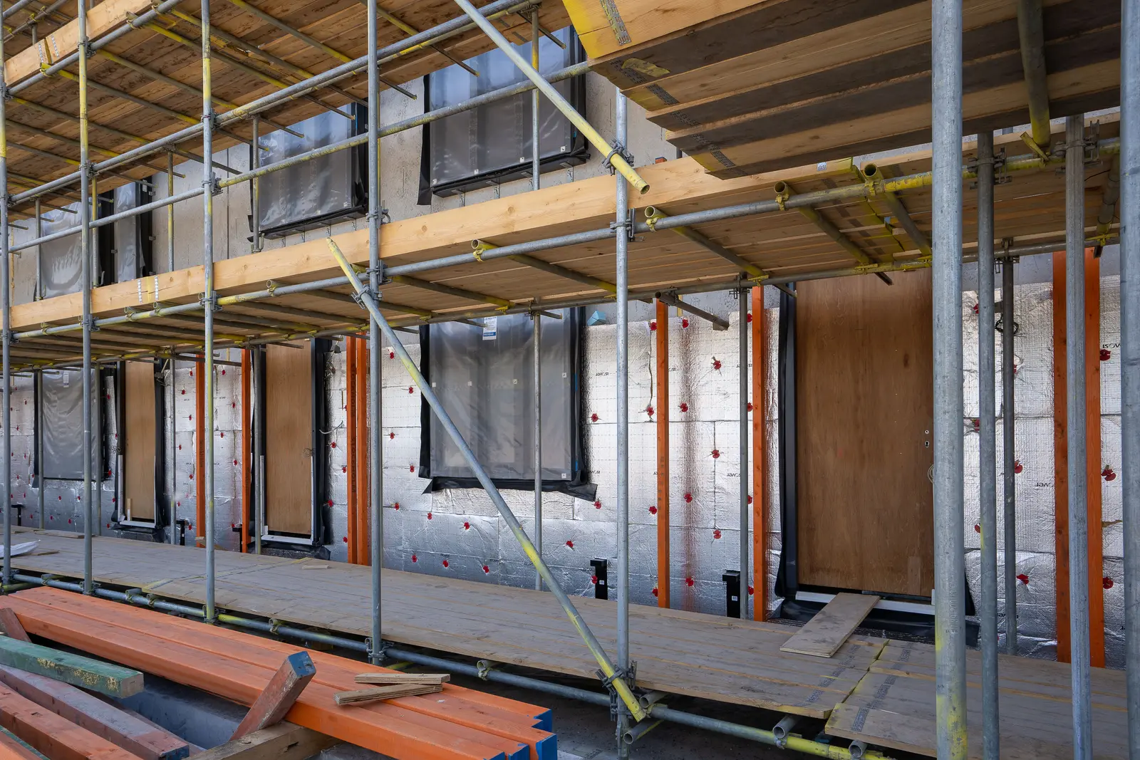 Wohngebäudefassade mit Gerüst und sichtbar montierten Dämmplatten rund um Fenster und Türen